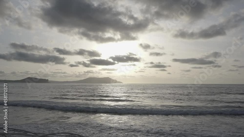 Coastal waves against the backdrop of sunrise and clouds in the sky. There is Meganom mount on the background. Novy Svet. Crimea.