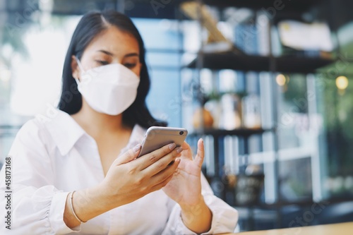 Close up Beautiful woman hands using smart phone in cafe, woman wearing surgical mask and use smart phone.