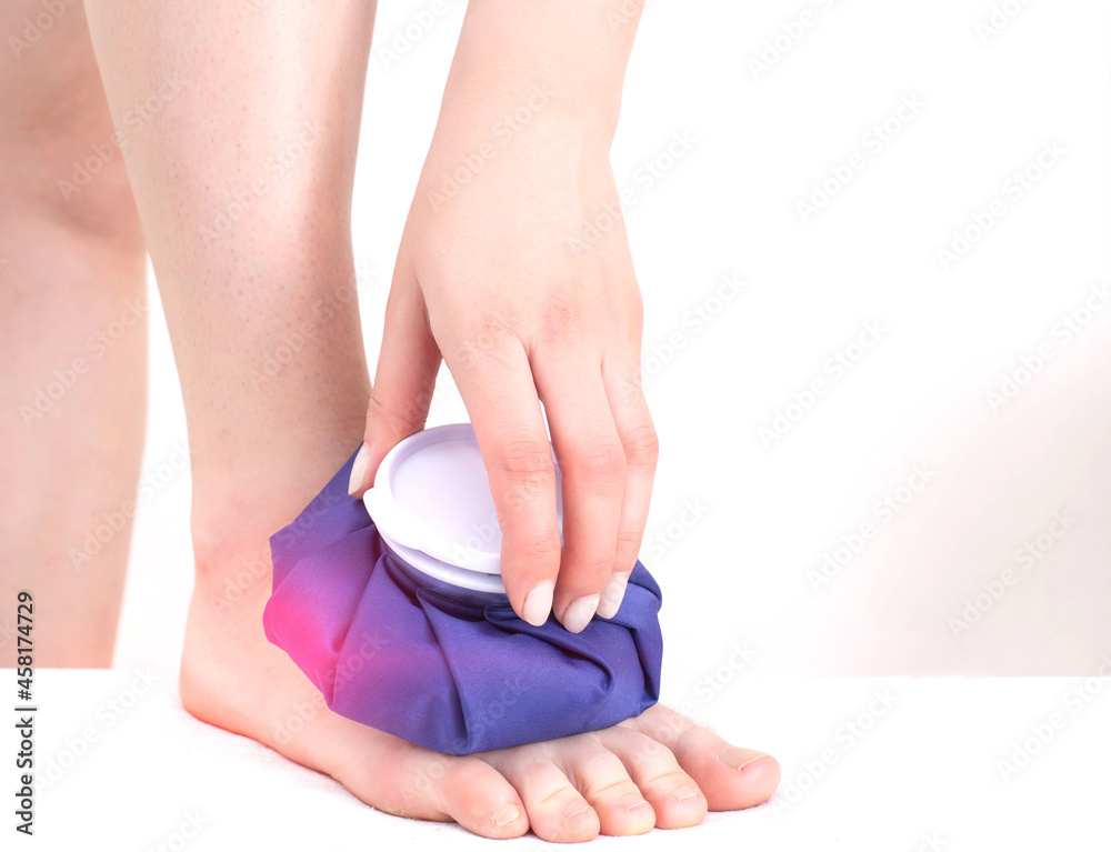 A girl applies a medical blue ice pack to the muscles of the lower leg to relieve pain and inflammation after a bruise, close-up A girl applies a medical blue ice pack to the muscles of the lower leg to relieve pain and inflammation after a bruise, close-up