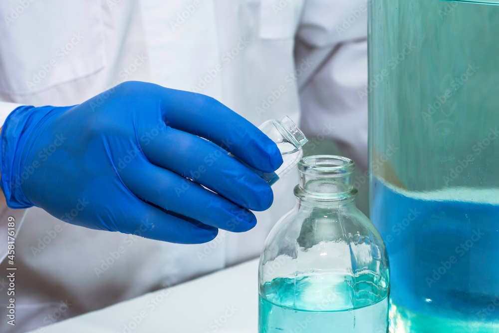 a doctor in the laboratory pours liquid from one bottle into another close-up a doctor in the laboratory pours liquid from one bottle into another close-up