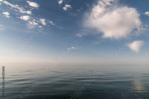 blue sky and clouds are reflected in the serene lake water