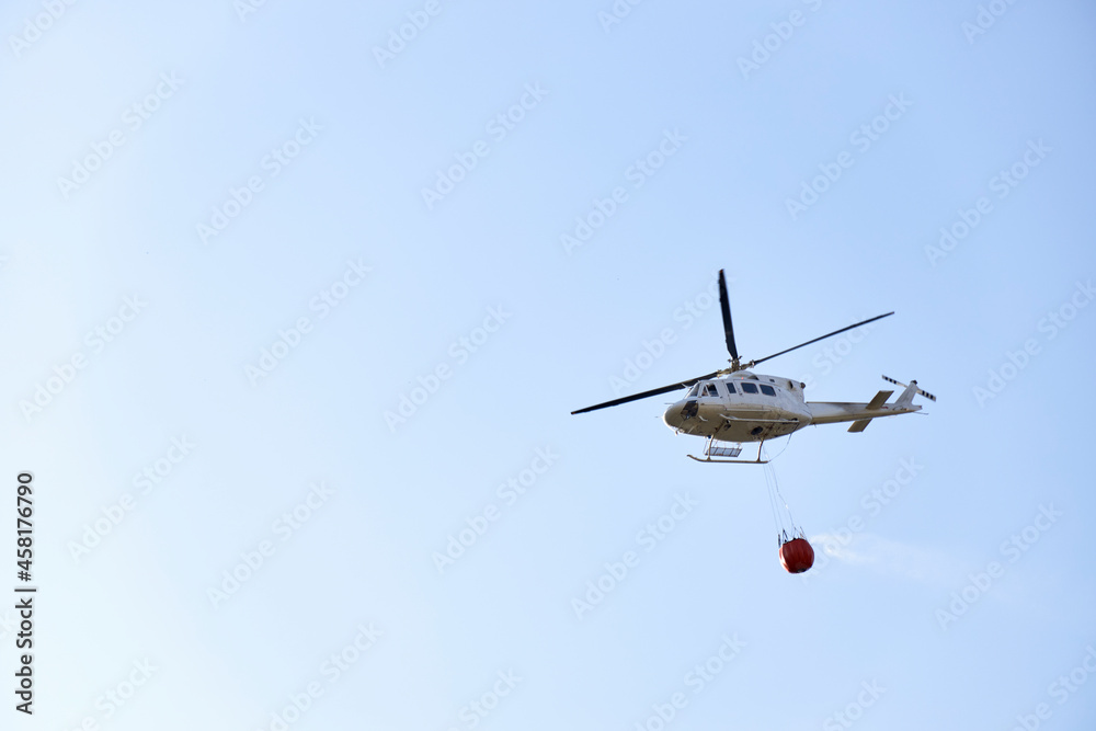 Firefighting helicopter transporting water to extinguish a fire. Hazard concept Firefighting helicopter transporting water to extinguish a fire. Hazard concept