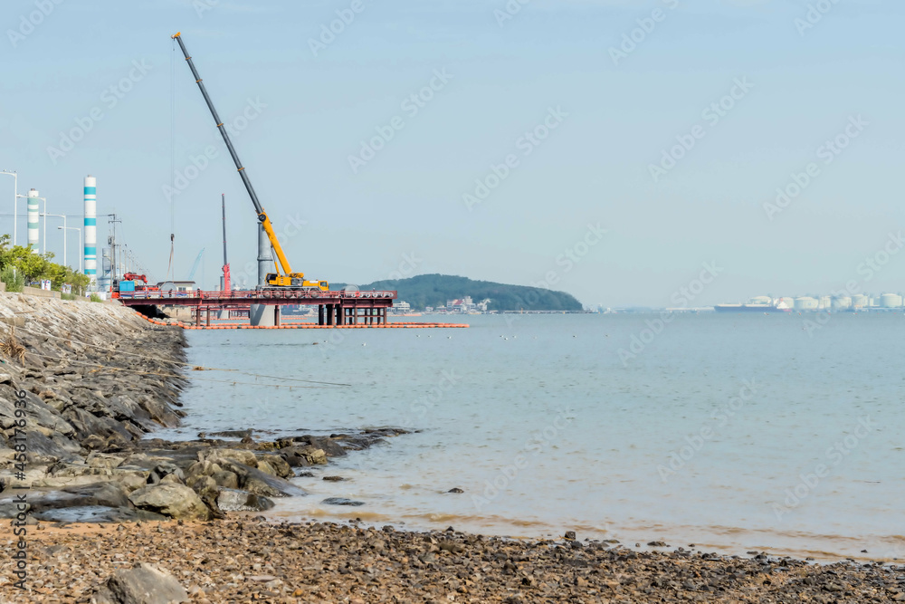 Construction crane on platform at edge of seacoast Construction crane on platform at edge of seacoast