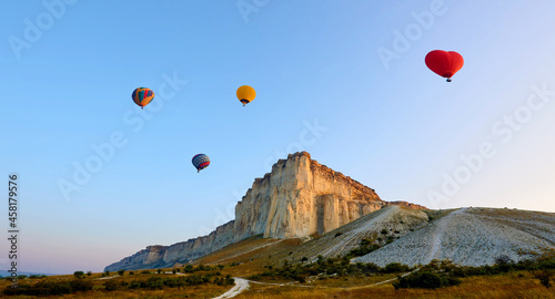 Landscape with colorful balloons at sunrise.