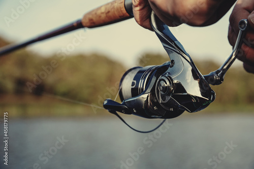 Fishing rod with a spinning reel in the hands of a fisherman. Fishing background