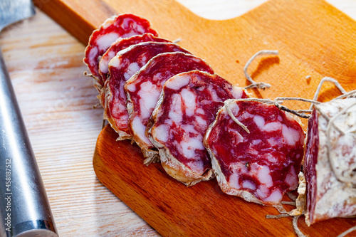 Photos Fresh italian piacenza salami cut in slices on a wooden surface, close-up