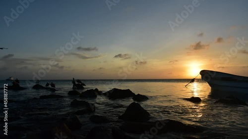Time Lapse Sunset  beach with Pelicans and silhouette of men in boat fishing. work task photo
