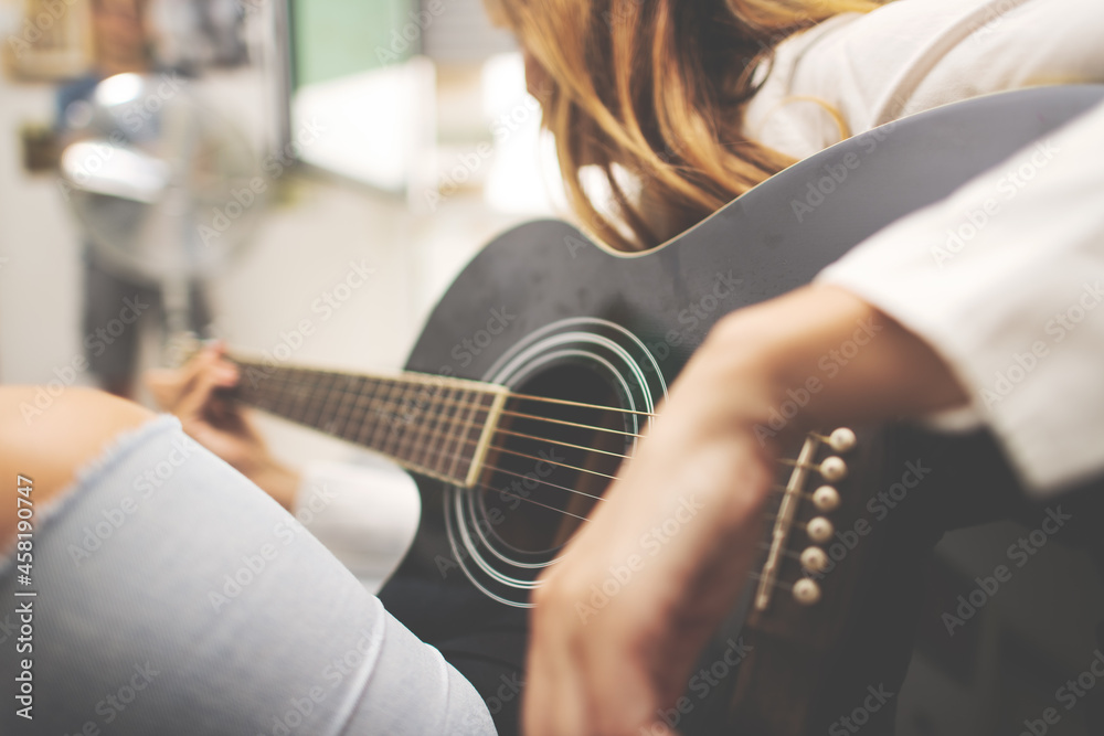 Fototapeta premium Acoustic guitar details in the hand of a left-handed woman