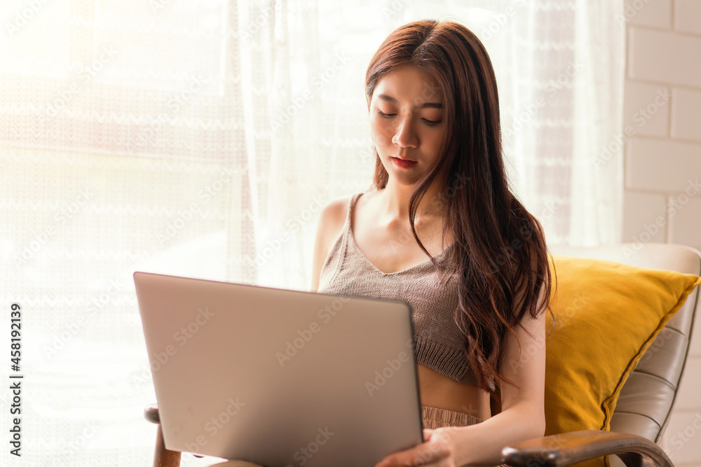 Asian woman relaxing sitting on sofa using computer notbeook at living room, Education technology and internet concept. Asian woman relaxing sitting on sofa using computer notbeook at living room, Education technology and internet concept.