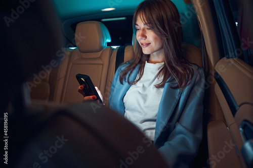 Fotografie Joyful woman using modern smartphone in car