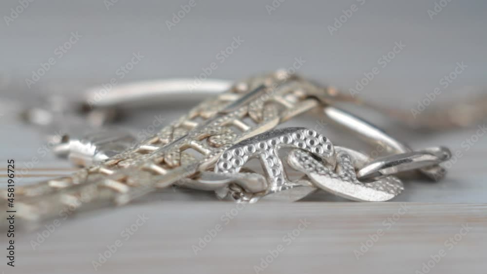 Silver chain moves slowly on a light background. Macro view. Shallow depth of field