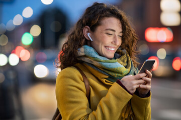 Woman on street using phone at evening