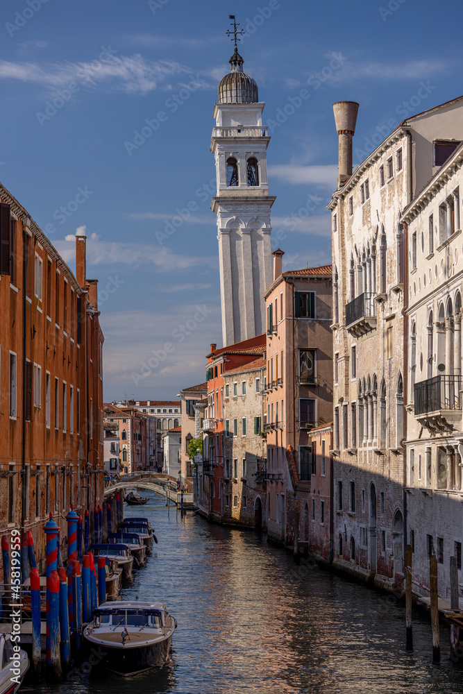 Venice, rio dei Greci canal and the leaning bell tower of the Church of Chiesa di San Giorgio dei Greci - old buildings, boats, bridges in the distance and a gondola