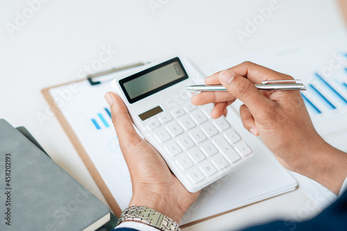 businessman working on desk office with using a calculator and laptop.