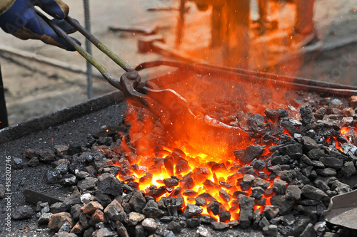 Blacksmith heats the metal workpiece on the blacksmith's furnace