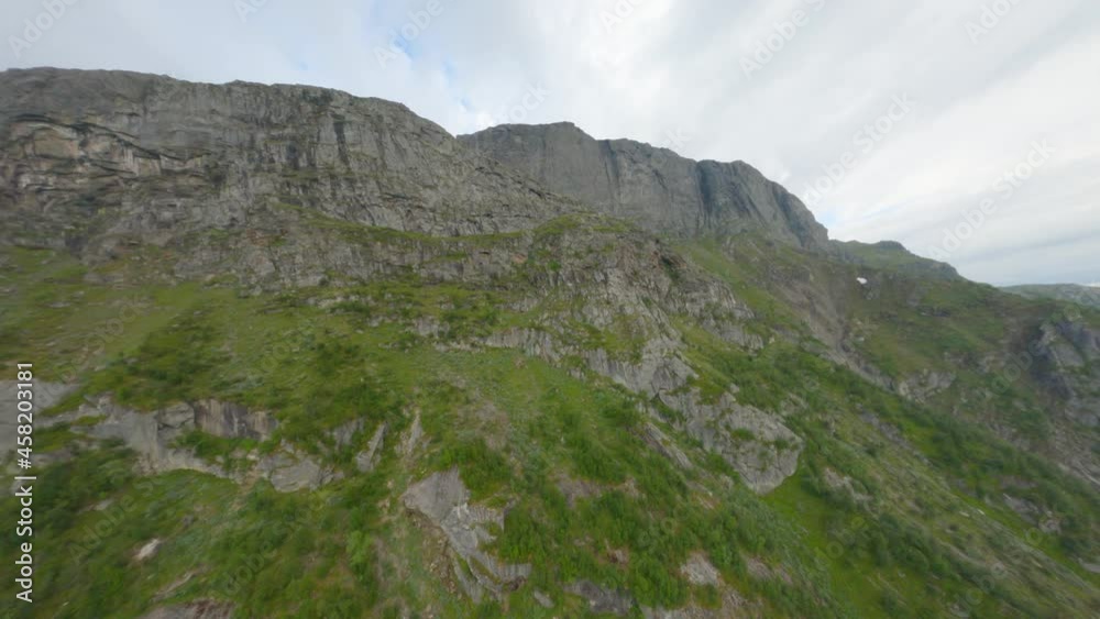 Drone flight along mountain range of with green plants against clouds in background - Rossnos Mountains,Europe - slow forward flight Drone flight along mountain range of with green plants against clouds in background - Rossnos Mountains,Europe - slow forward flight