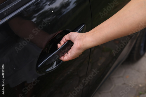 Close up of a female hand closing a car door at the dealership