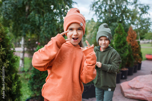 Kids in trendy hats and hoodies having fun in the park, fall vibes, autumn beauty style, child fashion, seasonal fashion. Outdoor active lifestyle