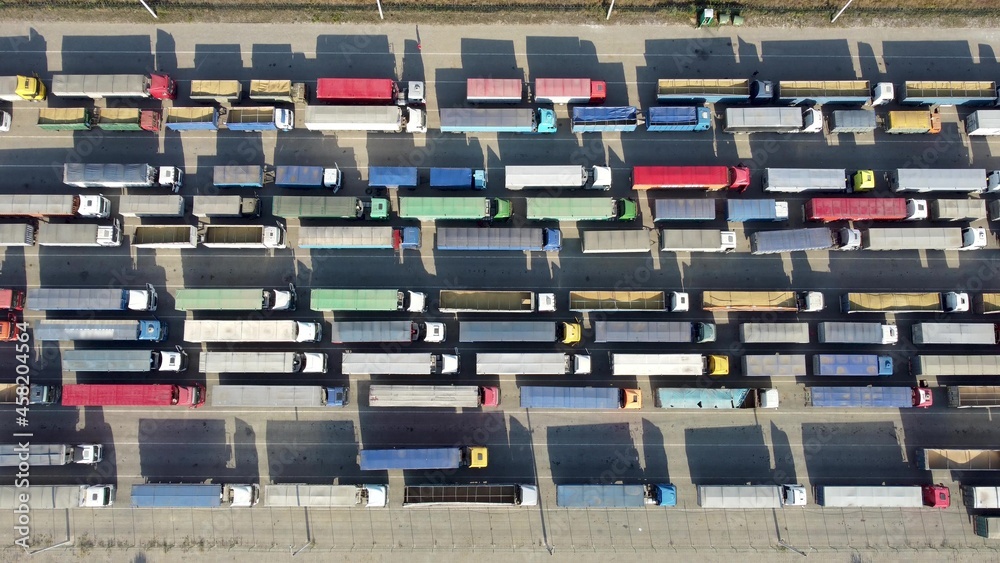 Fototapeta premium Top view of many trucks with trailers waiting to be unloaded at the port terminal.