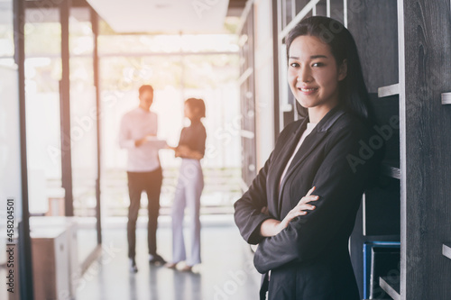 Portrait of asian business woman who standing in feeling happy at the office with daylight from window and blur garden background.