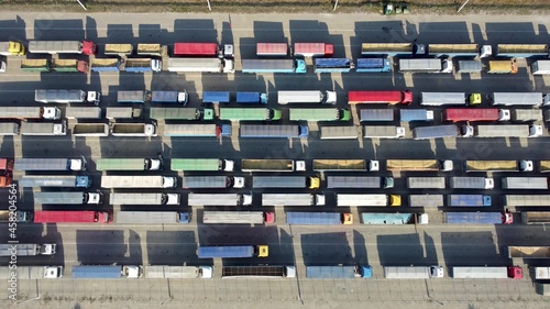 Top view of many trucks with trailers waiting to be unloaded at the port terminal.