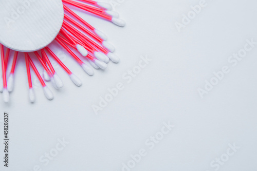 Disposable ear sticks with a red wand and white disposable cotton sponges lie on a white background. top view  flat lay  copy space  isolate