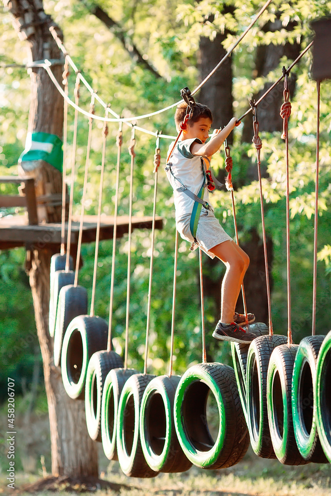 rope park. A boy passes an obstacle on tires in a rope Park.