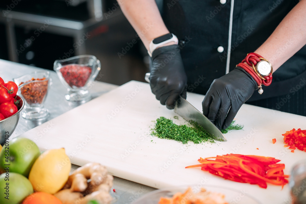 A Woman Chef cuts vegetables in the kitchen in a restaurant. A Woman Chef cuts vegetables in the kitchen in a restaurant.