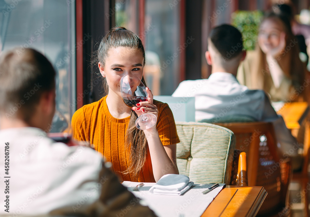 A young couple drinking wine in a restaurant near the window.