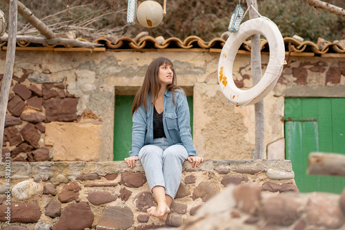 Caucasian girl sitting on fishing village wall looking out to sea