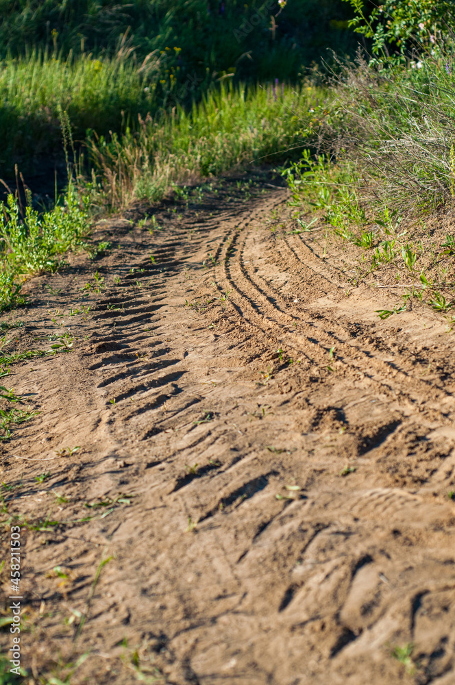 Rough road among grass and bushes. Traces from tractor on old dirt road close-up. Rough road among grass and bushes. Traces from tractor on old dirt road close-up.