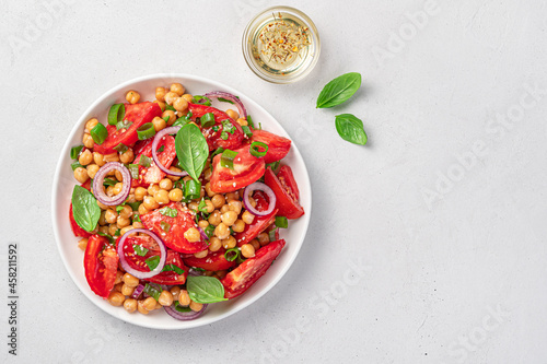 Salad with chickpeas  tomatoes  basil and sesame on a light gray background. Vegetarian  healthy food. Top view  copy space.