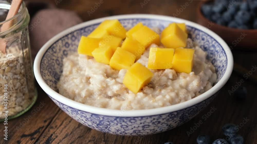 Add fresh mango into oatmeal porridge. Healthy vegan breakfast Add fresh mango into oatmeal porridge. Healthy vegan breakfast