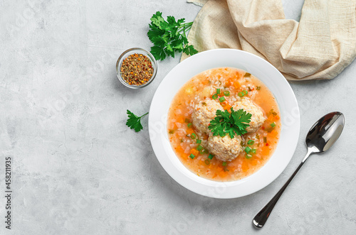 A portion of soup with meatballs, rice and vegetables on a light, gray background. Top view, copy space.