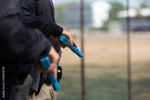 Police practice using blue rubber firearms in the lawn. 