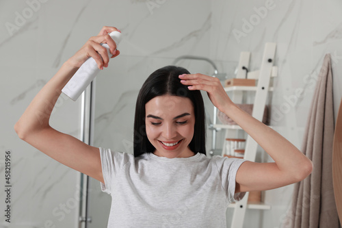 Vászonkép Woman applying dry shampoo onto her hair in bathroom
