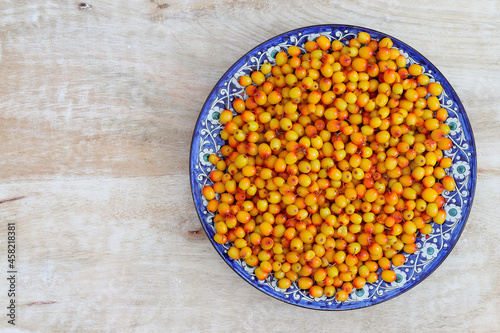 A plate of ripe sea buckthorn in a beautiful plate. Copy space