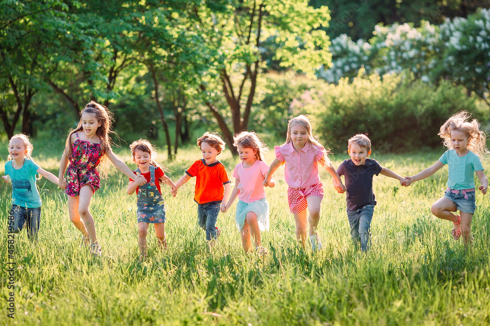 Fototapeta premium Large group of kids, friends boys and girls running in the park on sunny summer day in casual clothes .