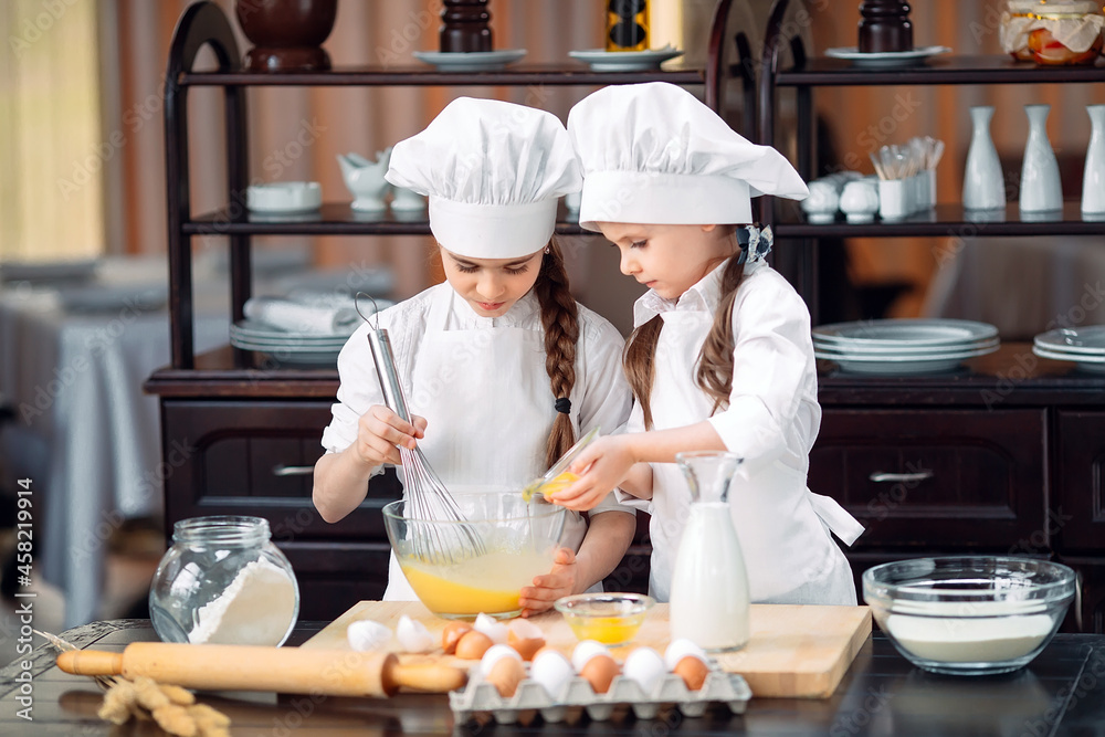 funny girls kids are preparing the dough in the kitchen. funny girls kids are preparing the dough in the kitchen.