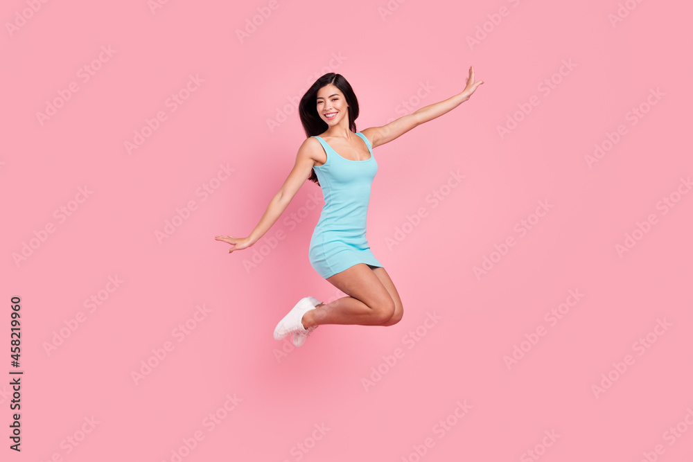 Full size profile photo of sweet young lady jump wear blue dress sneakers isolated on pink color background Full size profile photo of sweet young lady jump wear blue dress sneakers isolated on pink color background