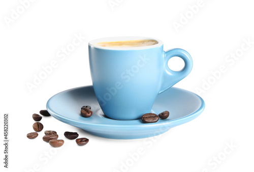 Cup of tasty espresso and scattered coffee beans on white background