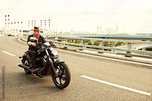 young man riding big bike ,motorcycle on city road against urban and town building scene. Motion blur