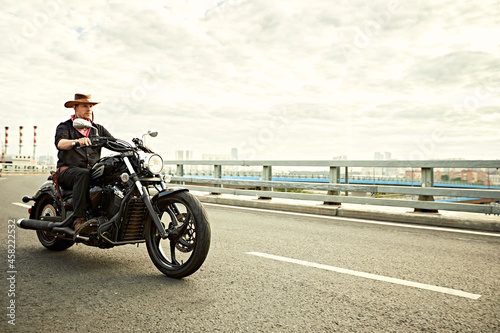 young man riding big bike  motorcycle on city road against urban and town building scene. Motion blur