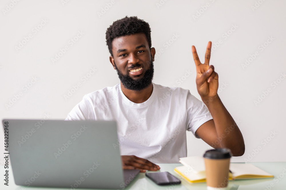 African american man working using laptop smiling with happy face winking at the camera doing victory sign. Number two. African american man working using laptop smiling with happy face winking at the camera doing victory sign. Number two.