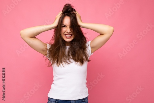 Portrait of positive cheerful fashionable woman in casual white t-shirt for mock up isolated on pink background with copy space © Ivan Traimak