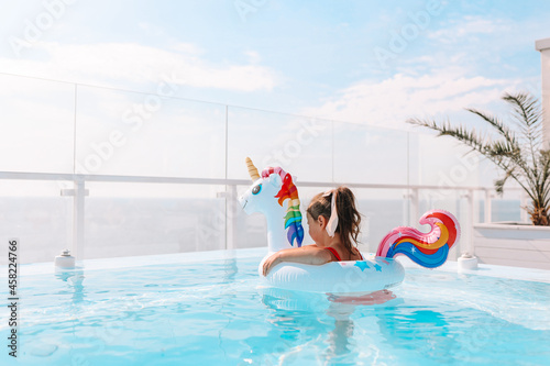 Little girl in a unicorn circle in a chic pool against the background of the sea
