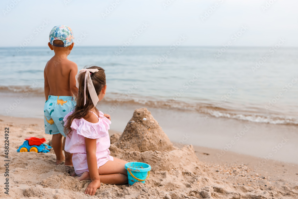 Children play on a tropical beach. Little girl digs sand on the seashore. Family summer vacation. Children play with toys made of water and sand. Ocean and island . Travel with small children. Children play on a tropical beach. Little girl digs sand on the seashore. Family summer vacation. Children play with toys made of water and sand. Ocean and island . Travel with small children.