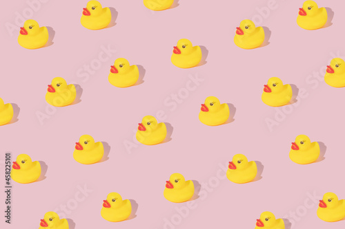Obraz na plátně Creative pattern made with yellow rubber duck  on pastel pink background