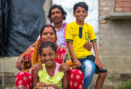 Canvas Print Indian Rural Parents and their two children sitting in front of the family house