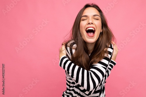 Photo shot of cute attractive pretty young delightful happy brunette woman wearing casual striped longsleeve isolated over colorful background with copy space
